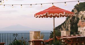 a table with a red umbrella and a view of the ocean at Il Capri Hotel in Capri +37 photos