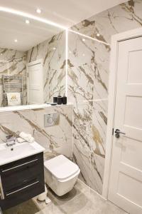 a bathroom with a white toilet and a sink at Pluxa Arctic - College Road Retreat with Full Apt Full Access in Harrow on the Hill