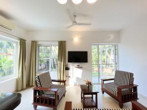 een woonkamer met 2 stoelen en een televisie bij Rainforest Enclave, Arpora - 10 mins to Baga beach in Arpora