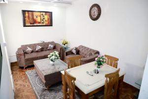 a living room with a couch and tables and chairs at Greenleaf Apartment and Suites, Chittaranjan Park in New Delhi