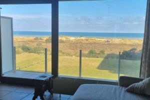 a bedroom with a large window with a view of a field at Superbe studio avec une magnifique vue sur la mer. in De Panne