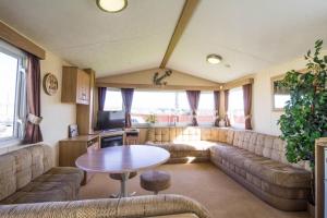 a living room with a couch and a table at Spacious 8 Berth Caravan At Heacham Beach Holiday Park In Norfolk Ref 21027b in Heacham