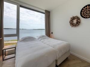a large bed in a room with a large window at Spacious waterfront apartment in Arnemuiden