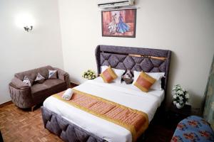 a bedroom with a large bed and a chair at Greenleaf Apartment and Suites, Chittaranjan Park in New Delhi