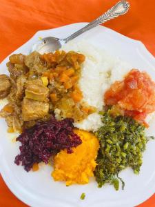 a plate of food with rice and vegetables on a table at Mphatlalatsane Executive BnB in Maseru