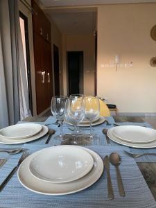 una mesa con platos blancos y copas de vino. en Appart Neuf et Lumineux à 2 Pas d'Angre Chu, en Abiyán