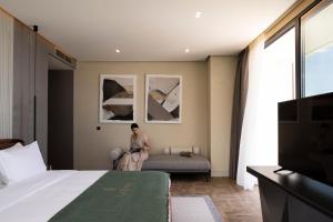 a woman sitting on a couch in a hotel room at La Brisa Boutique Hotel in Dhërmi