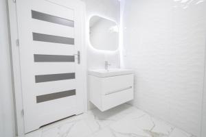 a white bathroom with a sink and a mirror at VacationClub - Zdrojowa 7 Apartament 5 in Duszniki Zdrój