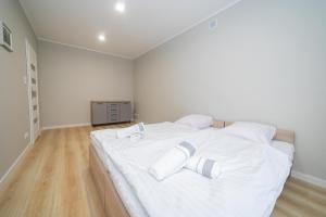 a white bedroom with a large white bed with white pillows at VacationClub - Zdrojowa 7 Apartament 4 in Duszniki Zdrój