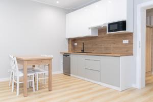 a kitchen with white cabinets and a table with chairs at VacationClub - Zdrojowa 7 Apartament 4 in Duszniki Zdrój