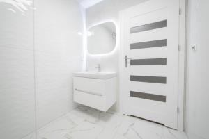 a white bathroom with a sink and a mirror at VacationClub - Zdrojowa 7 Apartament 3 in Duszniki Zdrój