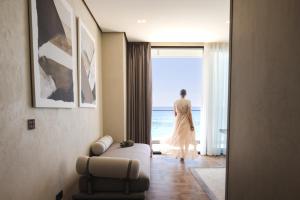 a woman walking out of a room looking out at the ocean at La Brisa Boutique Hotel in Dhërmi