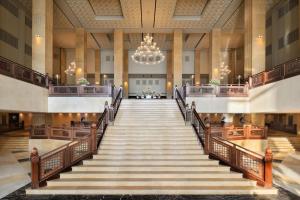 un escalier dans le hall de l'hôtel avec un lustre dans l'établissement Grand Hyatt Doha Hotel & Villas, à Doha