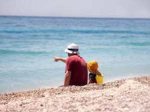 a man sitting on the beach pointing at the ocean at La Brisa Boutique Hotel in Dhërmi