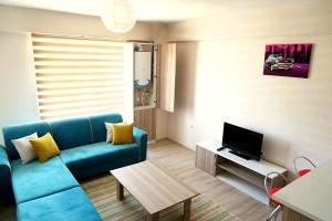 sala de estar con sofá azul y TV en Hayat Home Suite, en Erzincan