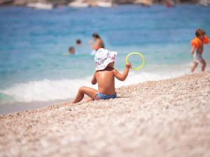 a young child playing with a frisbee on the beach at La Brisa Boutique Hotel in Dhërmi