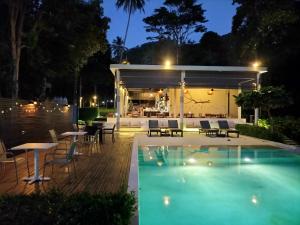a swimming pool at night with a patio with tables and chairs at Nest Sense Resort in Ko Chang