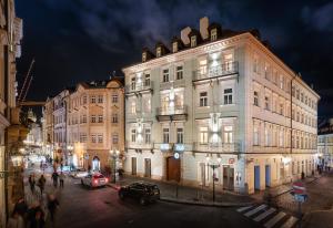 Golden Angel Suites by Adrez في براغ: مبنى ابيض كبير على شارع المدينة بالليل