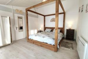 a bedroom with a wooden canopy bed in a room at Gîte du Midi de Saint-Porchaire - Charmante maison de vacances avec piscine chauffée in Saint-Porchaire