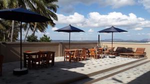 Ramena Beach Hotel في Ramena: مجموعة طاولات وكراسي مع مظلات على الفناء