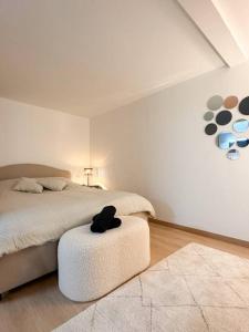 Un dormitorio con una cama y un taburete con un sombrero. en Mulhouse En Douceur, Hypercentre de Mulhouse, en Mulhouse
