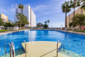 a large swimming pool with palm trees and buildings at Diana by IVI Real Estate in Benalmádena