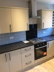 a kitchen with white cabinets and a stove top oven at Beautiful en-suite bedroom in Ipswich
