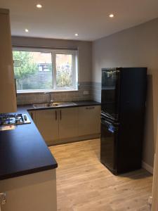 eine Küche mit einem schwarzen Kühlschrank und einer Spüle in der Unterkunft Beautiful en-suite bedroom in Ipswich