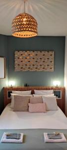Un dormitorio con una gran cama blanca y una lámpara de araña. en L'Emoustillant jacuzzi, unique et hors du temps, en La Richardais
