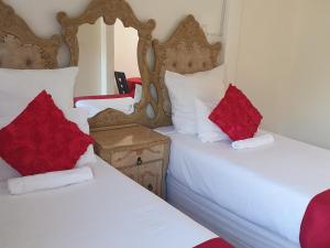 2 letti con cuscini rossi in una camera di Mesda Bed & Breakfast a Empangeni