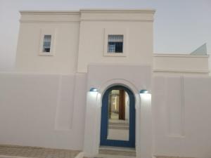 an entrance to a white building with a blue door at Diar Nader in Midoun