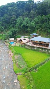 a building with a grass field next to a mountain at Chipau house Trạm Tấu in Cham Ta Lao