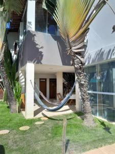 uma rede em frente a uma casa com uma palmeira em Pousada da Sami na Barra de São Miguel