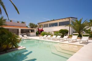 a swimming pool with chairs and a house at Ostuni a Mare in Ostuni