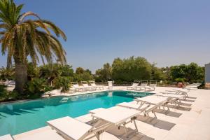 a pool with white lounge chairs and a palm tree at Ostuni a Mare in Ostuni