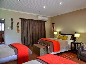 a hotel room with two beds and a chair at Winterfell Lephalale Lodge in Lephalale