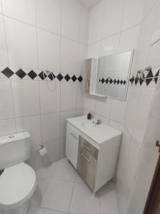 a white bathroom with a toilet and a sink at Casa Aconchegante em Itapema in Itapema