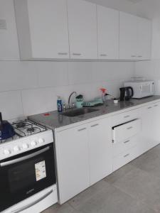 a white kitchen with a stove and a sink at En el Centro in Gualeguaychú