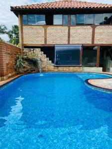 a large blue swimming pool with a house at Pousada Kyrios in Maresias