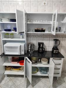 a kitchen with white cabinets and a microwave at Sobrado 4 dorm Cond. Fechado Praia da Mococa Caraguatatuba in Caraguatatuba