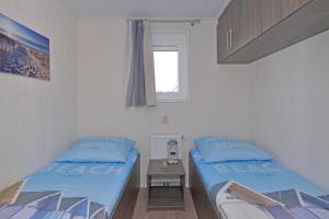 two beds in a small room with a window at Vakantiepark de Boomgaard in Westkapelle +110 photos
