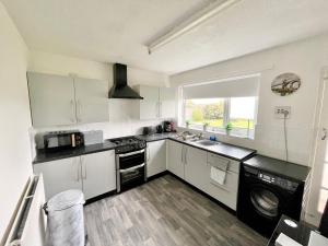 a kitchen with white cabinets and a stove top oven at South Stack Bungalow in Holyhead