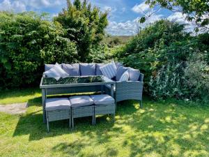 a garden bench with pillows on it in the grass at South Stack Bungalow in Holyhead