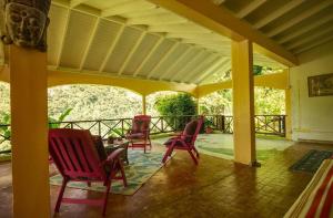 um alpendre com cadeiras vermelhas e um telhado em Aura Dominica em Roseau