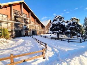 un bâtiment avec une clôture dans la neige dans l'établissement Charmant T2 - 6 pers - Chaillol 1600 - Balcon S/O - Parking - Animaux admis - Aire de jeux - FR-1-393-29, à Saint-Michel-de-Chaillol