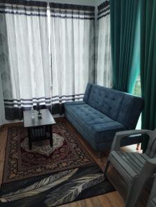 een woonkamer met een blauwe bank en een tafel bij Inap Idaman 7 5 Pax 2 Queen Plus 1 Sofa Bed in Kota Bharu