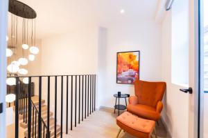 une chaise orange dans un couloir à côté d'un escalier dans l'établissement The Maida Vale, à Londres