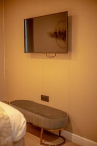 a tv on a wall with a ottoman in a bedroom at Hotel Holloway in Birmingham