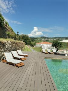 a deck with lounge chairs next to a swimming pool at Quinta de Travassinhos- Douro Valley in Santa Marta de Penaguião