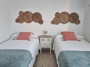 a room with two beds and a small table with a night stand at Ático con encanto in Baena